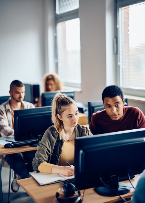 Young students cooperating while e-learning during computer class at the university.